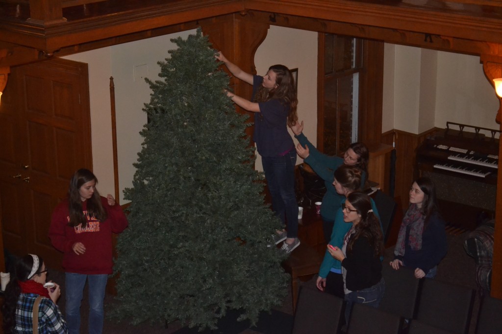 A group of MC students help set up the Christmas tree in the CCM. Sophie Lively, a junior, climbed up to straighten branches. Photo Courtesy of Shelby Sparks