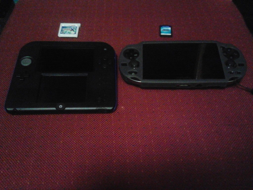A size comparison of the latest version of the 3DS, the 2DS (left), and the current version of the Vita (right). The physical copies of the games are shown above their respective consoles. Photo Courtesy of Shawn Richards