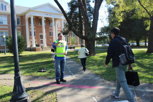 Josh Anderson “directs” traffic with the help of a powerful neon yellow vest in one of the most annoying sidewalk intersections on campus. The neon vest represents authority and power so individuals have no choice but to obey traffic commands. Photo courtesy of Ariana Hansen.