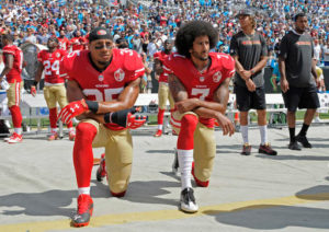 Teammates Eric Reid (L) and Colin Kaepernick (R) kneel during the national anthem to protest anti-black state violence. Photo courtesy of Mike Cam/Associated Press.