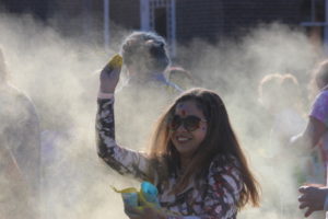 Sezim Altynbek gets ready to throw yellow Holi powder through the cloud of color.